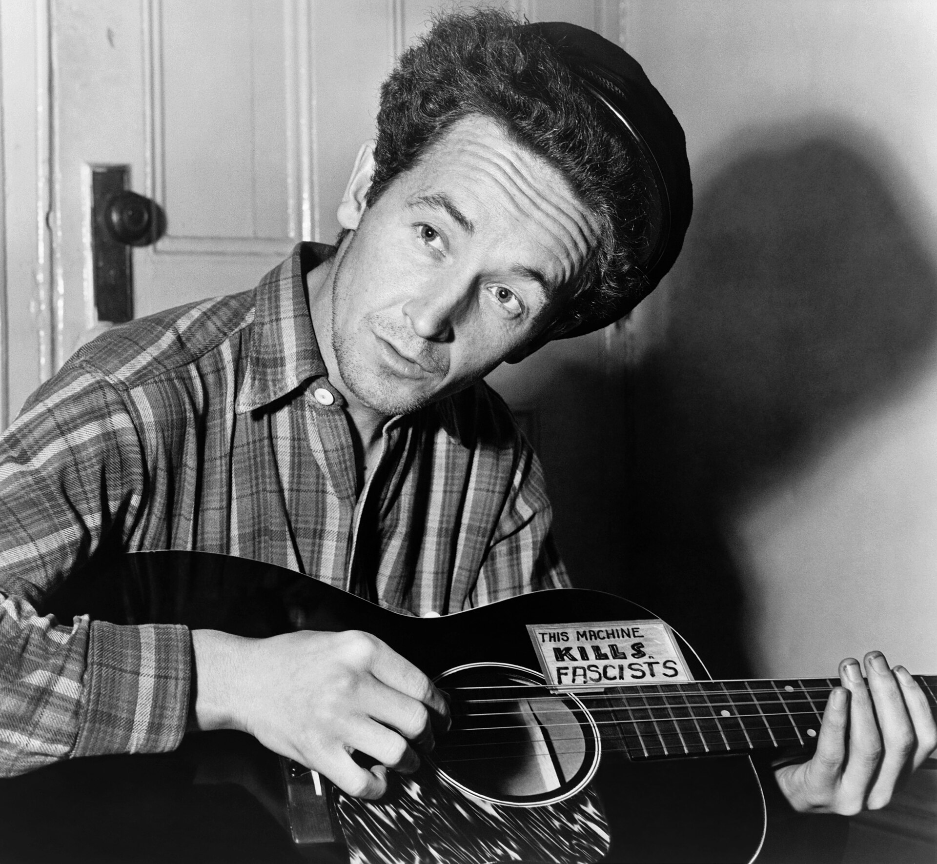 Il cantautore Woody Guthrie con la chitarra